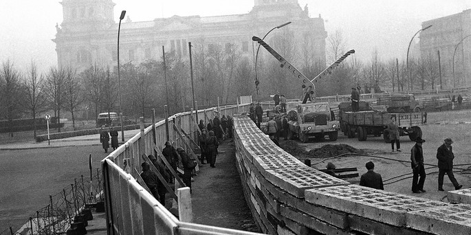 Trabajadores y máquinas construyen una de las fases del muro de Berlín mientras los soldados montan guardia