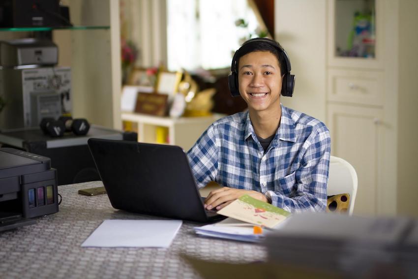 Adolescente haciendo tareas escolares en casa usando su computadora portátil