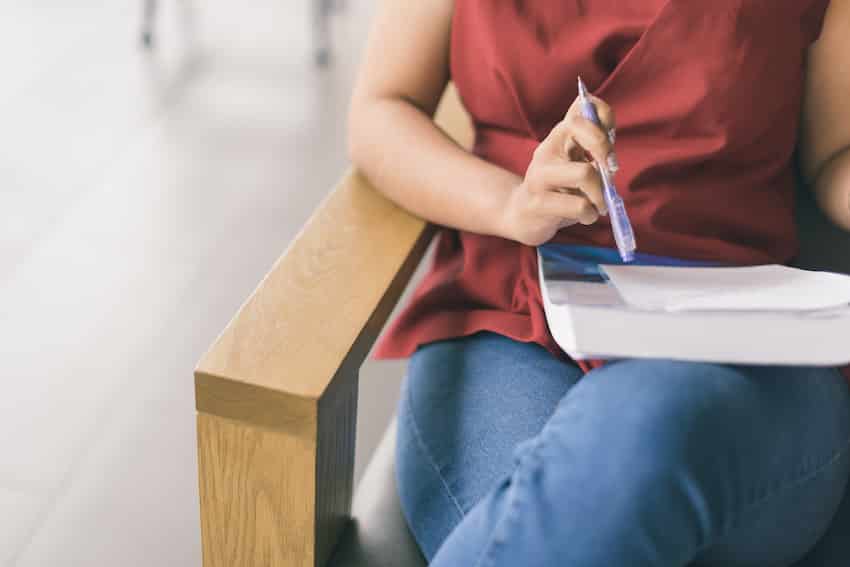 Tutor de estadística: una estudiante se sienta en una silla con su libro, papel y bolígrafo