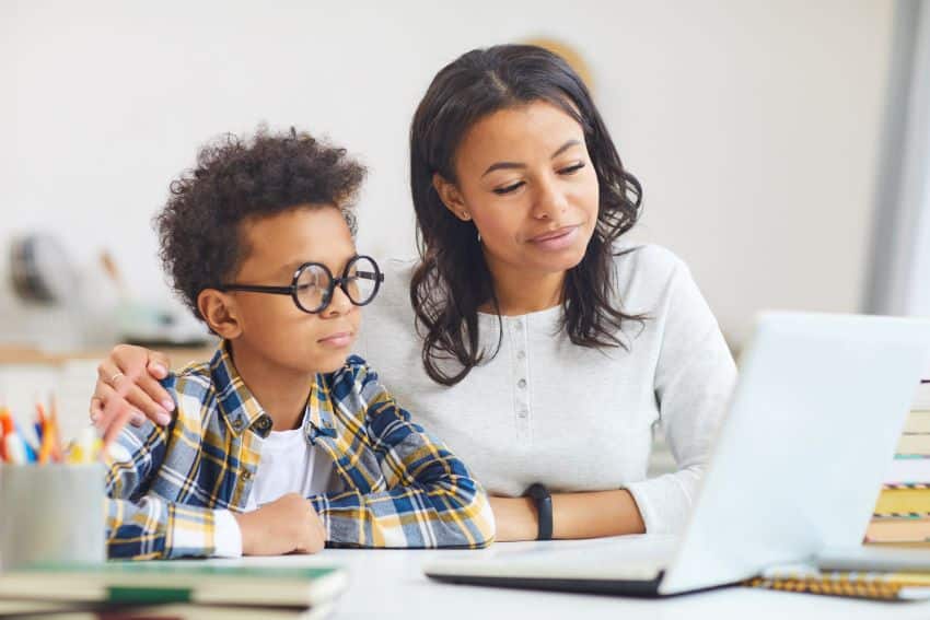 Encuentra un tutor: niño negro usando una computadora portátil con su madre
