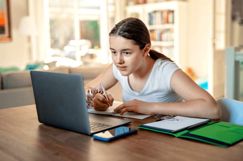propiedad distributiva de la multiplicación: niña tomando notas mientras mira su computadora portátil